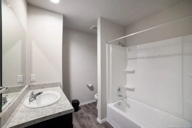 a bathroom with a granite countertop sink and a bathtub