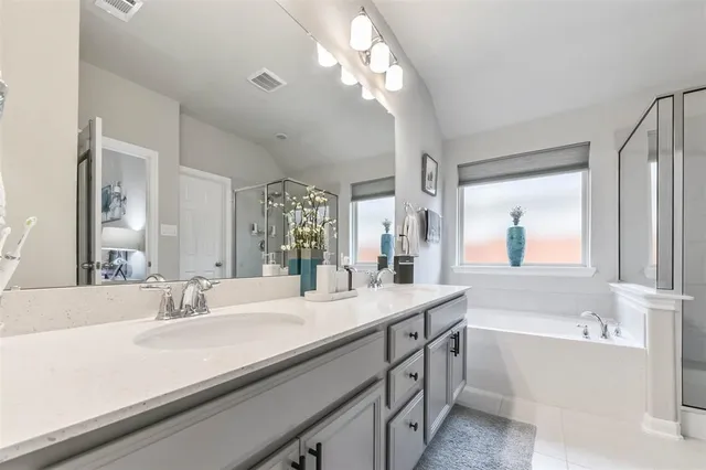a bathroom with a sink double vanity granite tub and a mirror