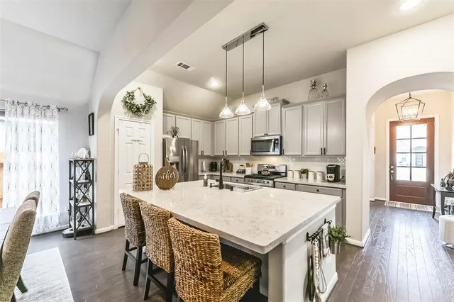 a kitchen with sink a refrigerator and chairs