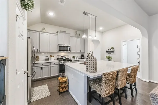 a kitchen with kitchen island a stove a table and chairs in it