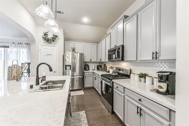 a kitchen with stainless steel appliances granite countertop a sink a stove top oven a refrigerator with cabinets and wooden floor