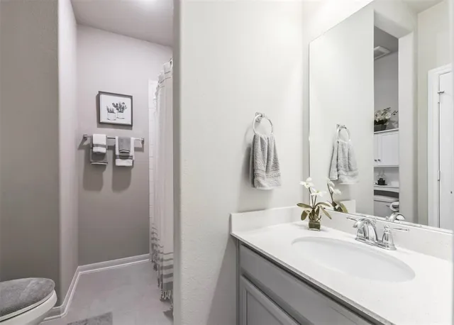 a bathroom with a granite countertop sink toilet and mirror