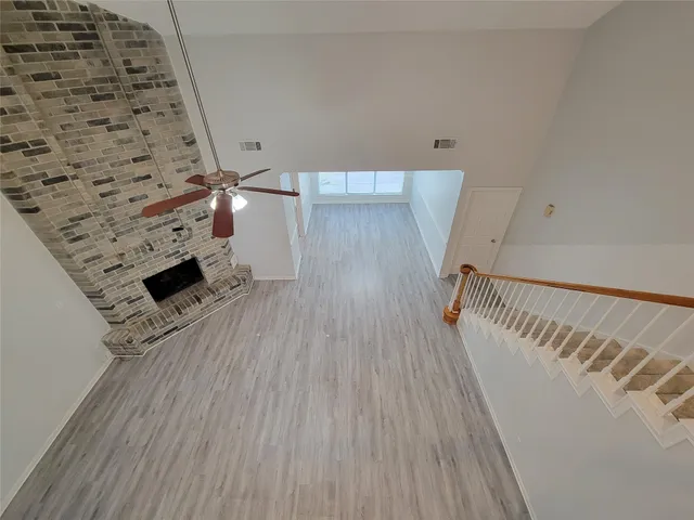 an empty room with chandelier fan and windows