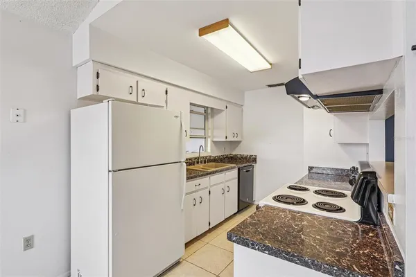 a kitchen with granite countertop a refrigerator a stove and a sink