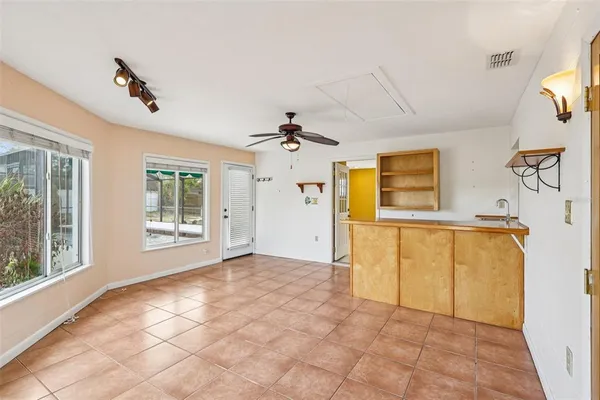 a view of an empty room with window and chandelier fan