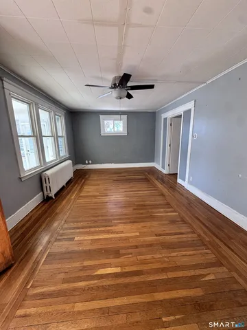 a view of an empty room with window and wooden floor