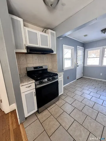 a kitchen with granite countertop a stove a sink and a microwave