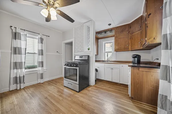 a kitchen with granite countertop a stove a sink and white cabinets with wooden floor
