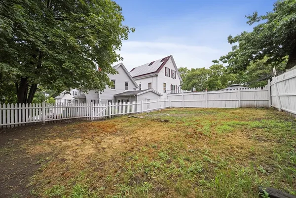 a view of a house with a yard and a large tree