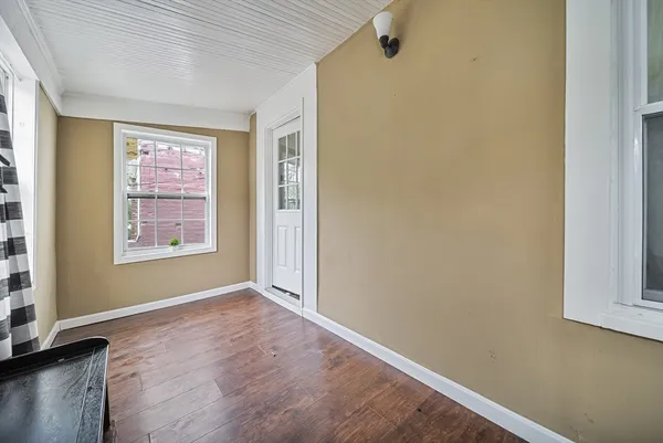 a view of an empty room with a window and wooden floor