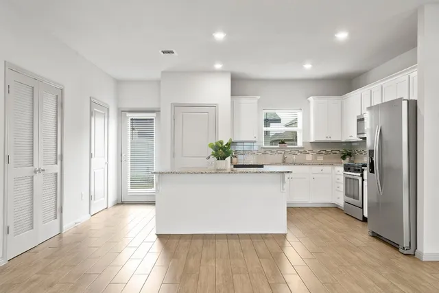 a kitchen with stainless steel appliances granite countertop a refrigerator sink and white cabinets
