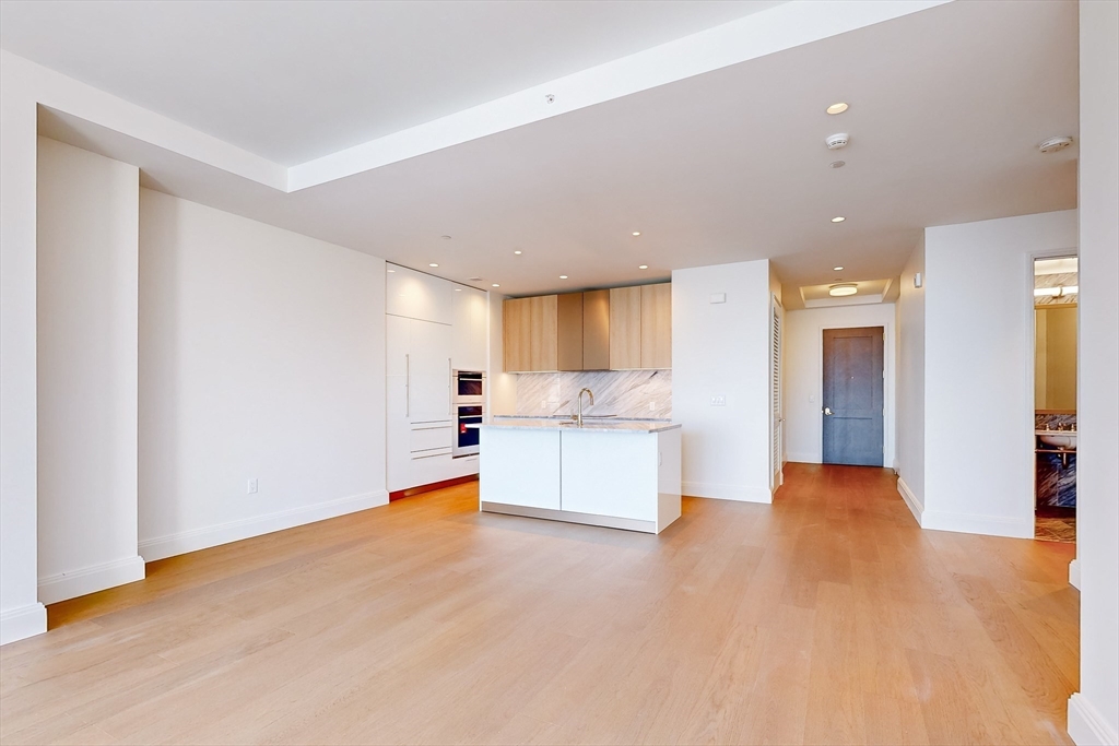 240 Devonshire Street, Unit 5011 Boston, MA 02110 - Photo 5 of 39 a view of an empty room and kitchen with granite countertop stainless steel appliances