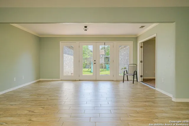 an empty room with wooden floor and a bathroom view