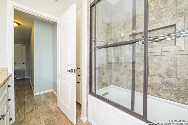 a bathroom with a granite countertop sink a mirror and a shower