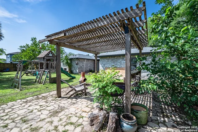 a backyard of a house with plants and large tree