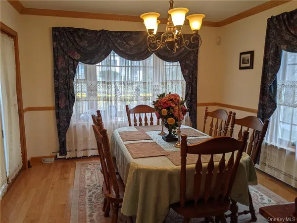 a view of a dining room with furniture a chandelier and wooden floor