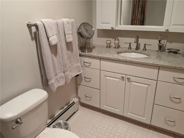 a bathroom with a granite countertop toilet sink and mirror