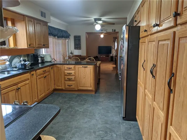 a kitchen with stainless steel appliances granite countertop a refrigerator a sink dishwasher a stove and white countertops with wooden floor