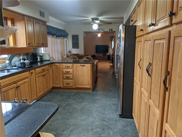 a kitchen with stainless steel appliances granite countertop a refrigerator a sink dishwasher a stove and white countertops with wooden floor