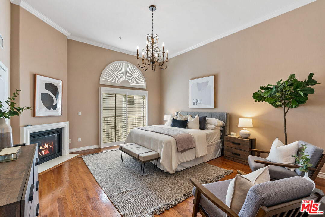 1747 South Barrington Avenue, Unit 103 Los Angeles, CA 90025 - Photo 21 of 45 a spacious bedroom with bed a chandelier and a fireplace