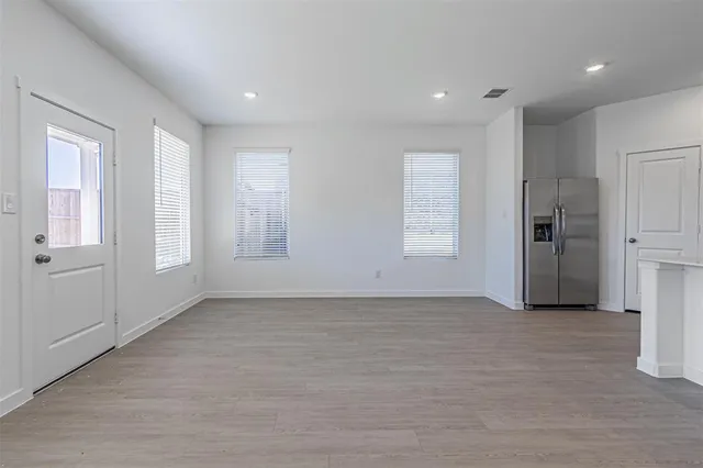 an empty room with windows and refrigerator