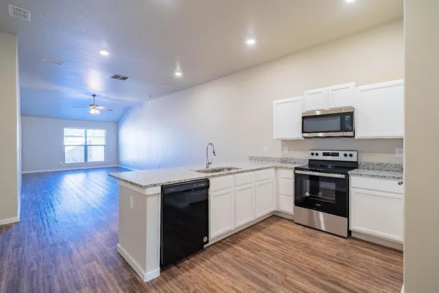 a kitchen with granite countertop a stove top oven and cabinets