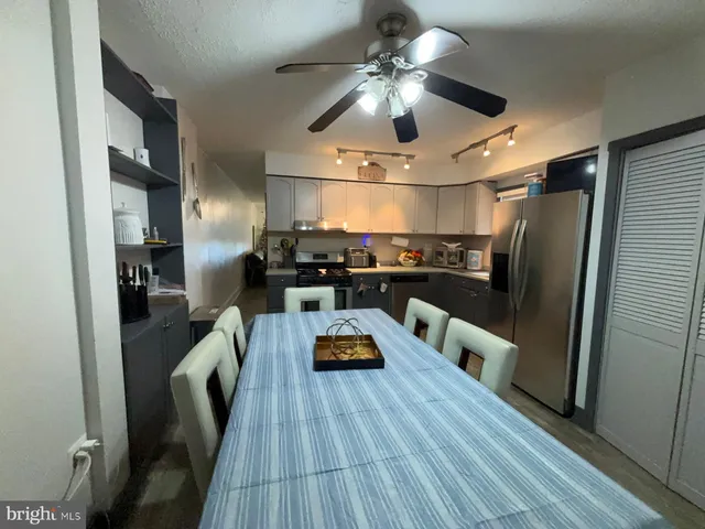 a kitchen with stainless steel appliances kitchen island granite countertop a refrigerator a stove and a sink with wooden floor