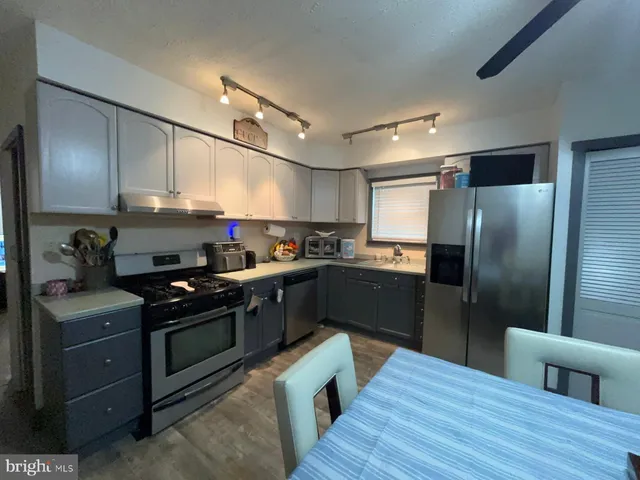 a kitchen with stainless steel appliances granite countertop a refrigerator a stove and a wooden floors