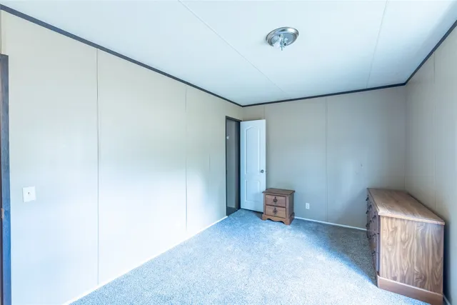 a view of a hallway with wooden floor and a bathroom
