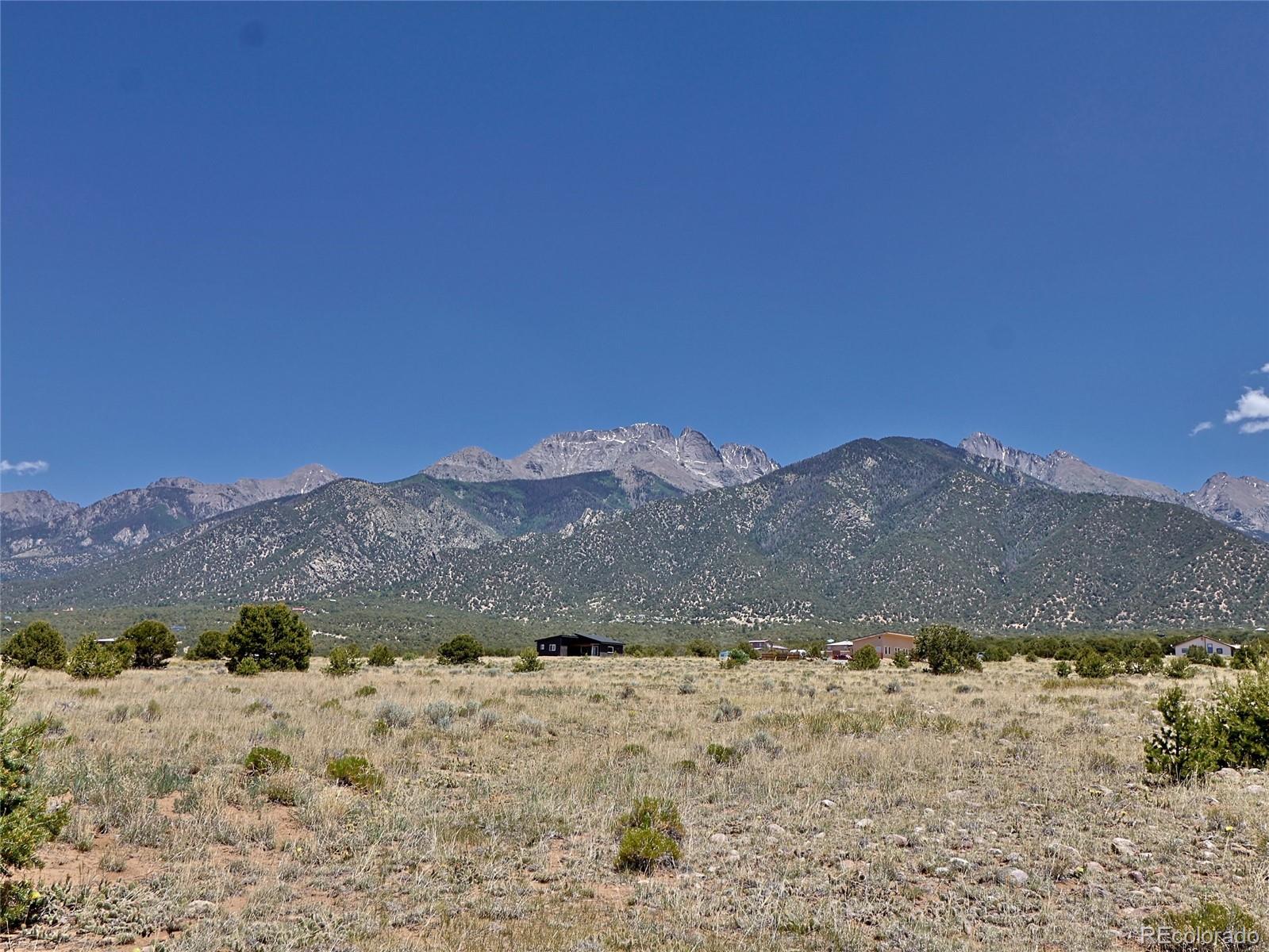 a view of a dry field with mountains in the background