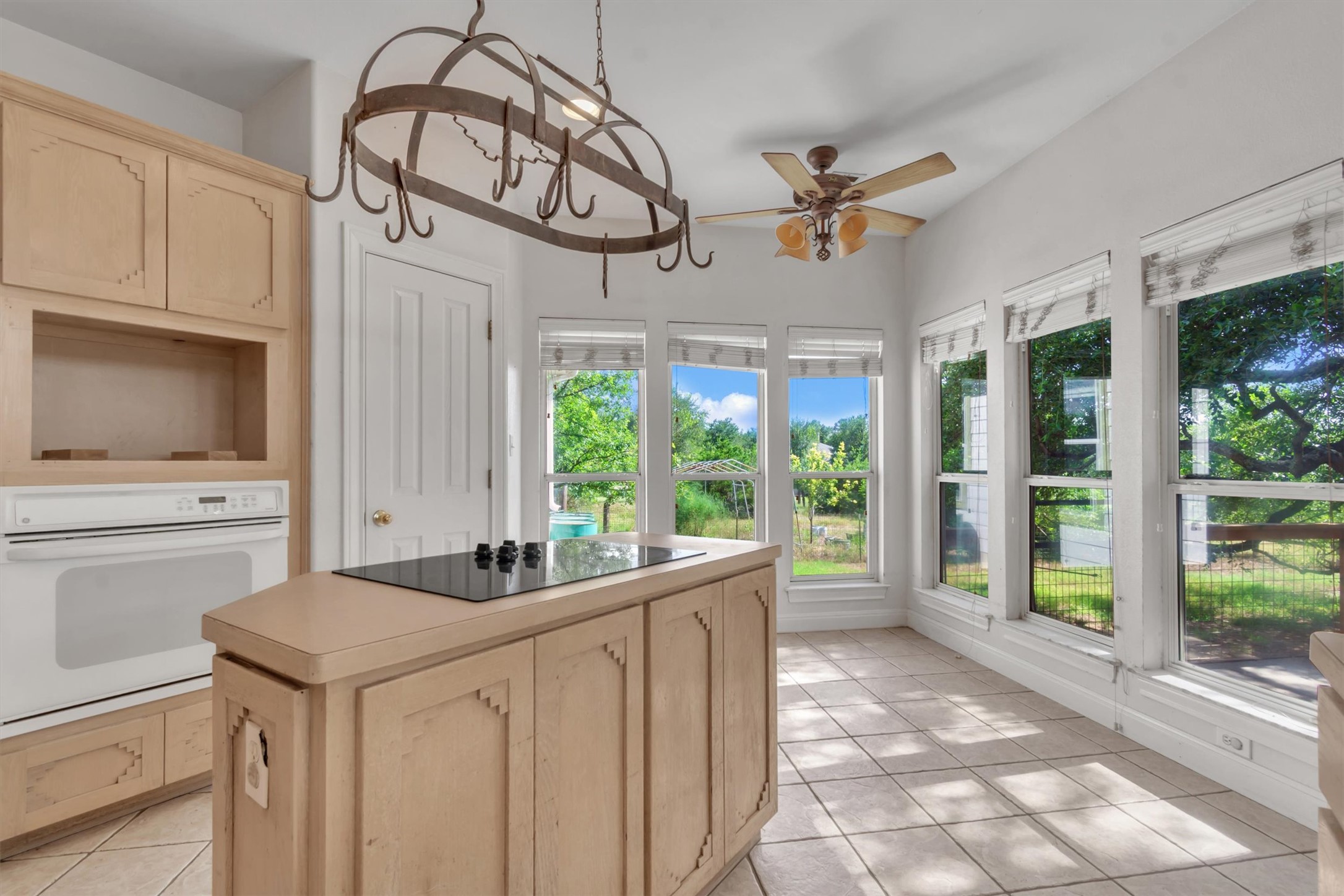 1120 Meadow Ridge Drive Austin, TX 78737 - Photo 13 of 40 A well-lit kitchen with extensive window views features a central island cooktop and tiled flooring.
