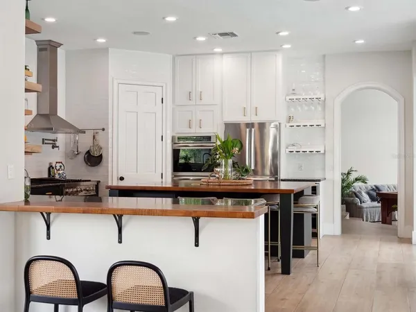 a kitchen with stainless steel appliances granite countertop a stove a sink dishwasher and a dining table with wooden floor