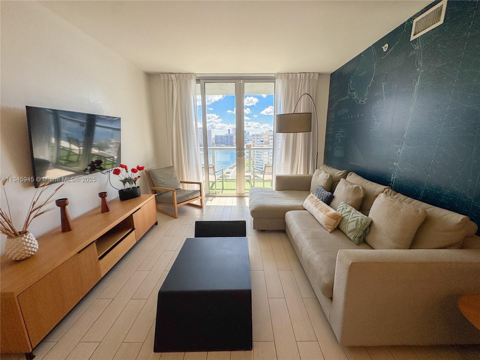 2602 East Hallandale Beach Boulevard, Unit R1409 Hallandale Beach, FL 33009 - Photo 8 of 32 a living room with furniture and a flat screen tv