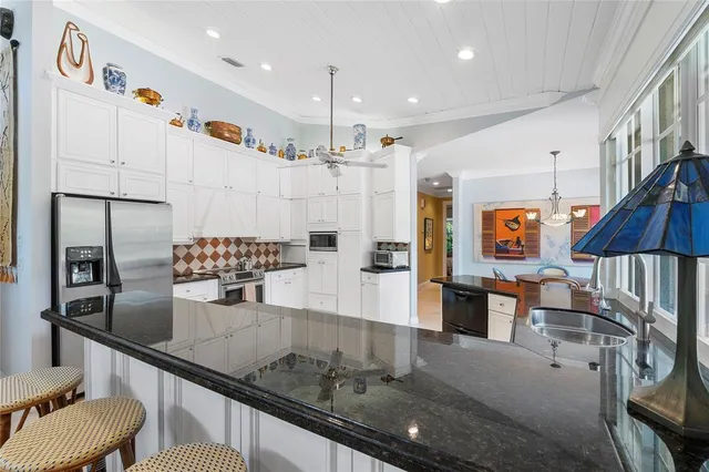 a kitchen with stainless steel appliances granite countertop a stove a refrigerator a oven a sink with a dining table and chairs