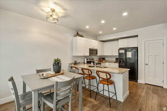 287 North 100th West Morgan, UT 84050 - Photo 12 of 27 Kitchen featuring light stone counters, a peninsula, stainless steel appliances, light wood-style flooring, and a breakfast bar area