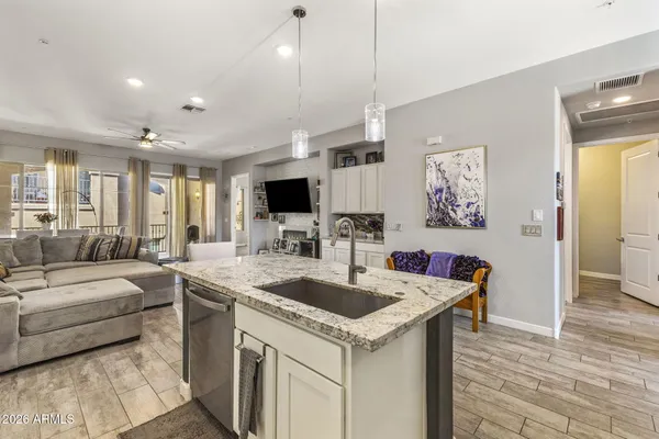a kitchen with granite countertop a sink a counter top space and living room view