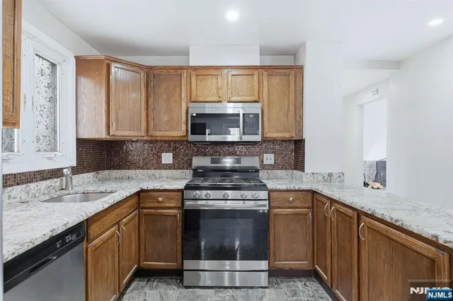 a kitchen with stainless steel appliances granite countertop a sink stove and microwave