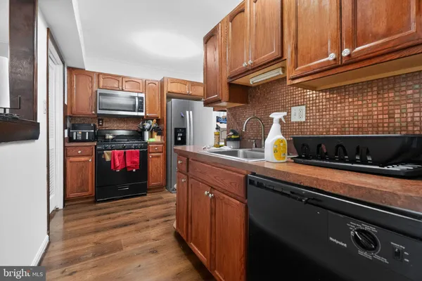 a kitchen with stainless steel appliances a sink dishwasher a stove top oven a refrigerator and cabinets with wooden floor