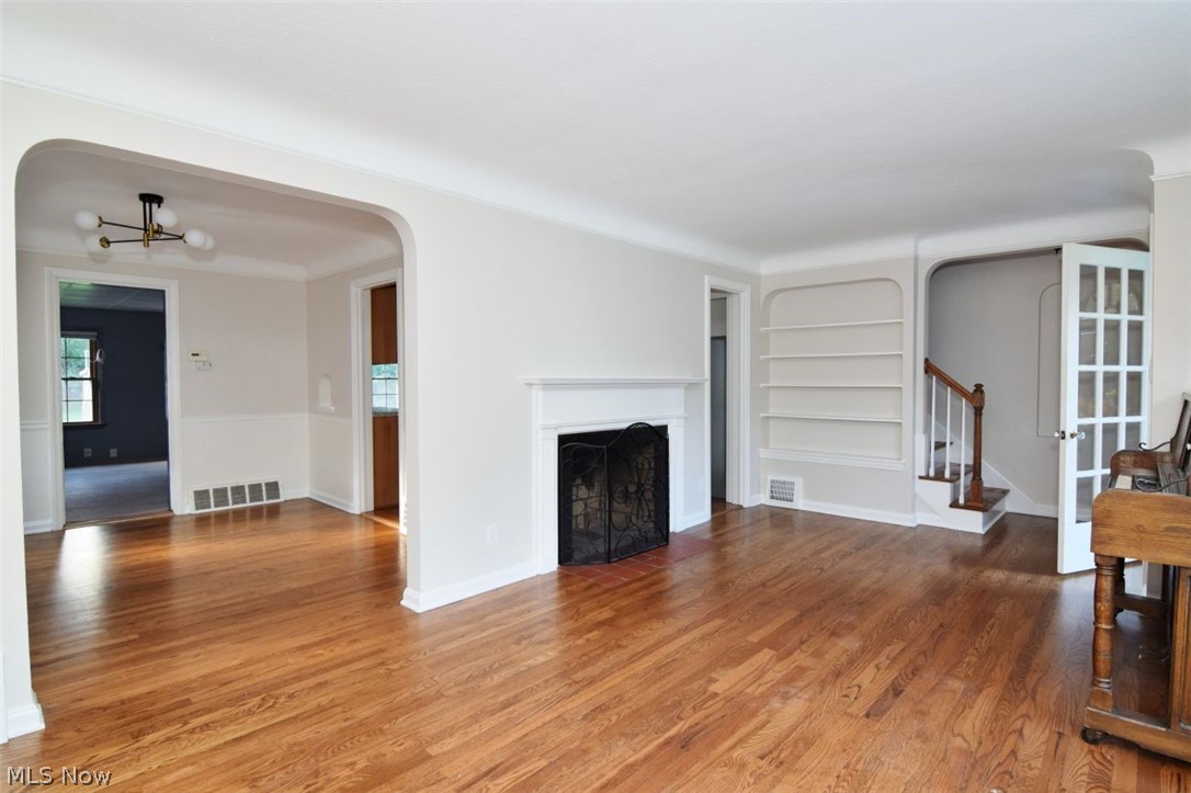 5284 Edenhurst Road Lyndhurst, OH 44124 - Photo 9 of 50 Hardwood flooring throughout, a traditional fireplace with a decorative screen, built-in shelving, an arched entryway, and a staircase with wood railing