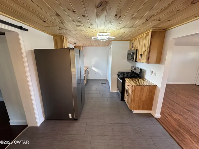 a kitchen with stainless steel appliances granite countertop a refrigerator a stove a sink and a window