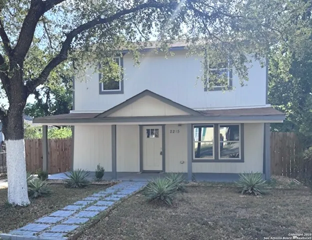 a view of a house with a yard and large tree
