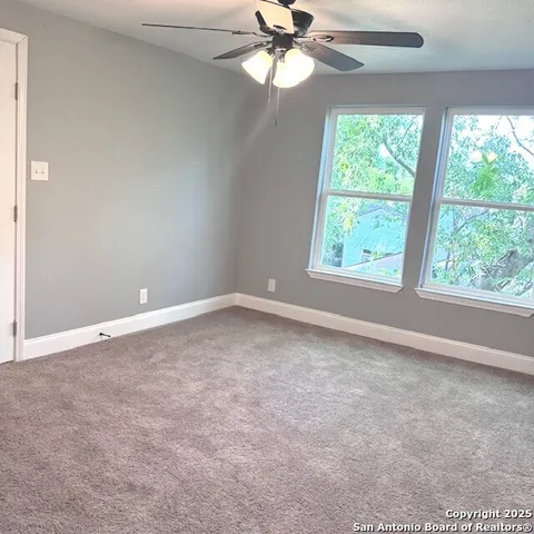 an empty room with a window and a fan