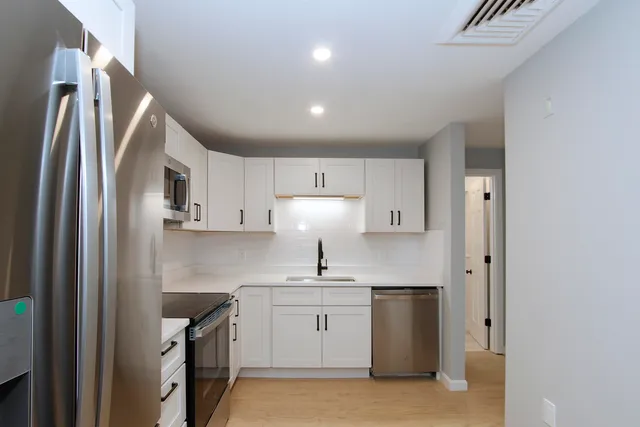 a kitchen with white cabinets and stainless steel appliances