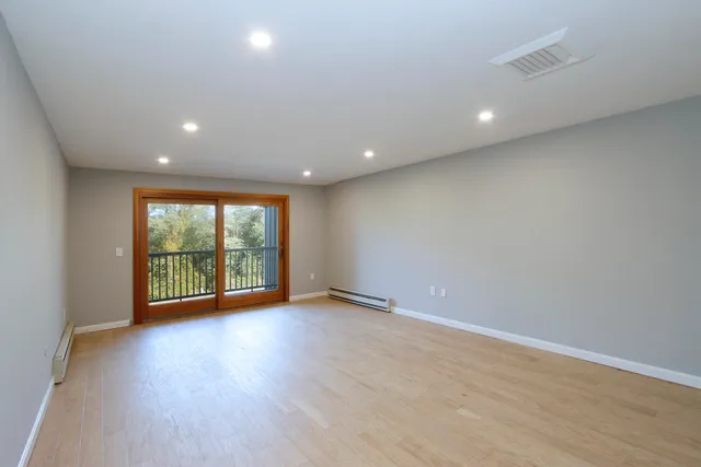an empty room with wooden floor and windows