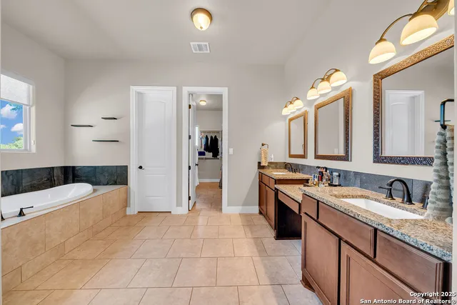 a large bathroom with a granite countertop double vanity sink a mirror and a bathtub