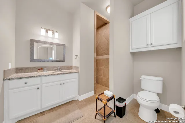 a bathroom with a granite countertop toilet sink and mirror