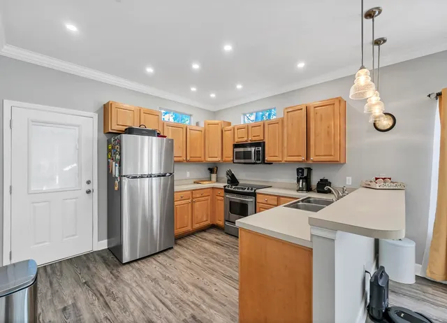 a kitchen with a refrigerator a sink and wooden floor