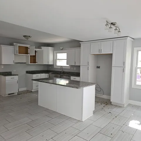 a kitchen with granite countertop white cabinets and white appliances
