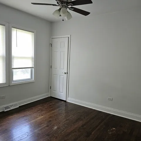 an empty room with wooden floor closet and windows