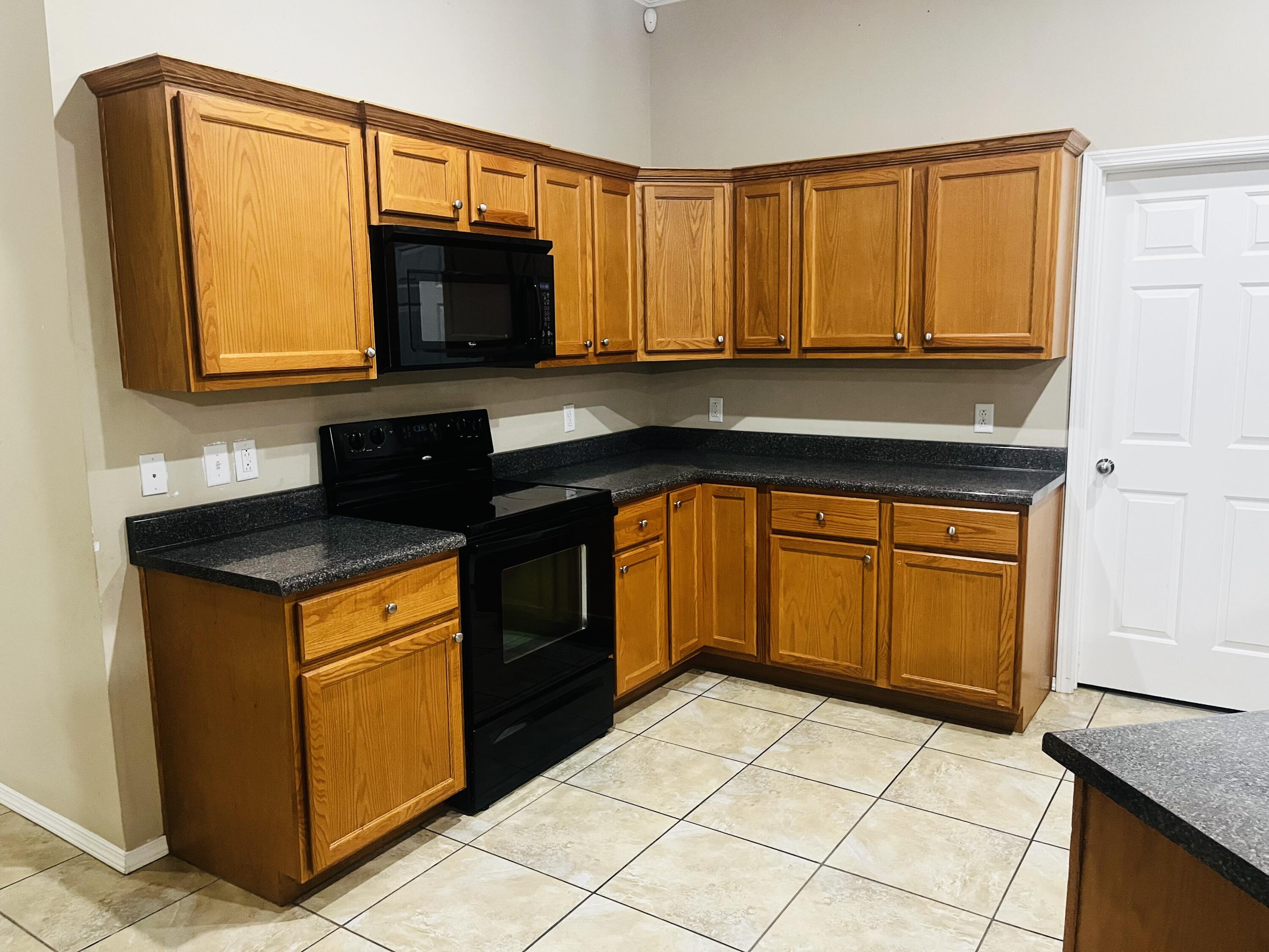 10016 Weatherford Avenue Lubbock, TX 79423 - Photo 3 of 29 a kitchen with granite countertop a stove a sink and a microwave